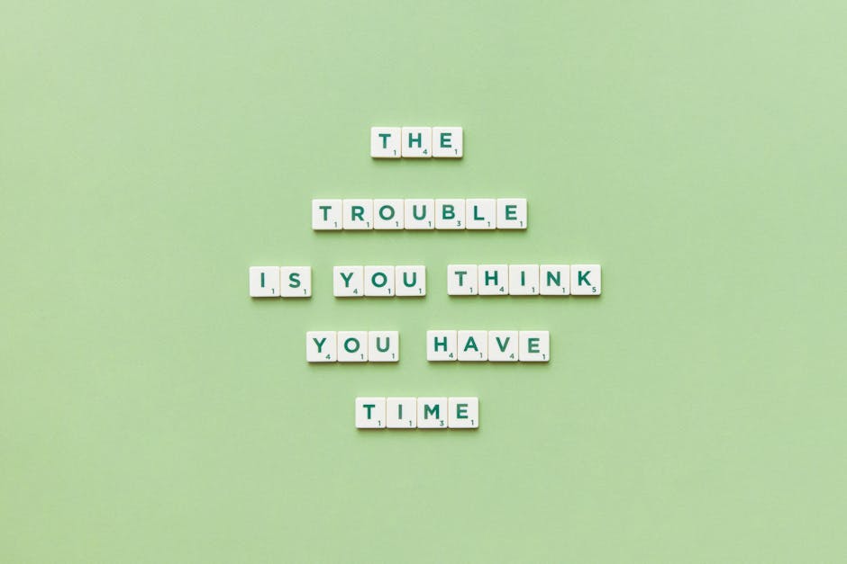 An arrangement of white letter tiles with black lettering spells out the phrase 'THE TROUBLE IS YOU THINK YOU HAVE TIME' on a light green background. The tiles are organized in a centered layout, with